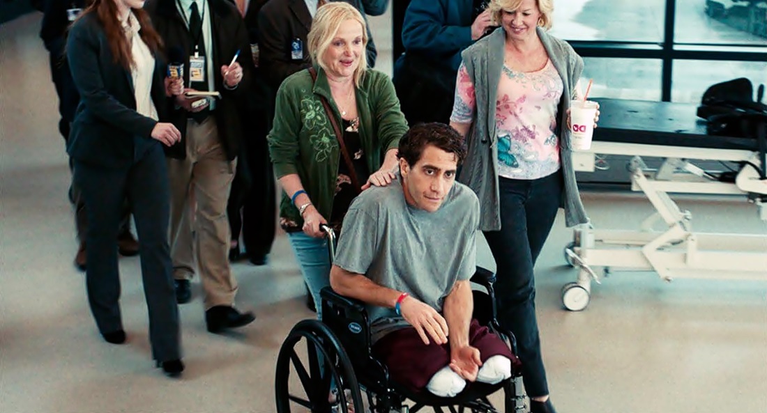 Escena de la película “Stronger” (Más fuerte que el destino), el protagonista se le ve sin piernas y en silla de ruedas, empujado por 2 mujeres mientras los siguen varios periodistas. 