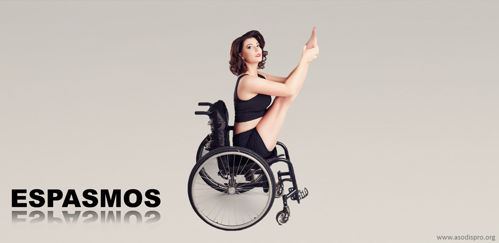 Una mujer de mediana edad está en una silla de ruedas, con traje como de gimnasia, levantando una pierna con una de sus manos.