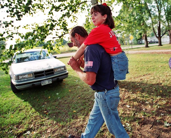 En un parque el señor Bricker lleva cargada en la espalda a Jennifer como de 12 años.