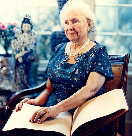 Ya cómo adulto mayor, Helen posa en una fotografía a colores mientras lee un libro con sus dedos.