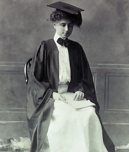 En un estudio fotográfico Helen Keller posa sentada, con la cabeza un tanto agachada y vistiendo una toga y un birrete.