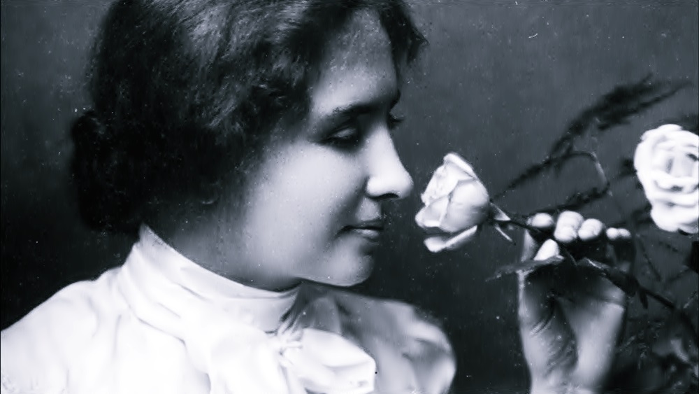 En un acercamiento de su rostro, Helen Keller cómo de 20 años huele una rosa.