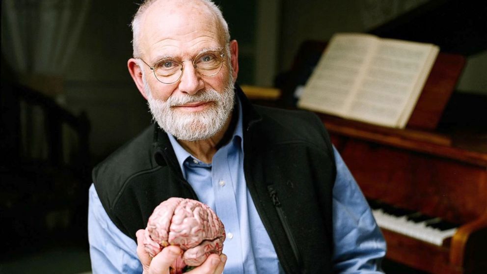 Viendo de frente a cámara, Sacks sostiene el modelo de un cerebro humano