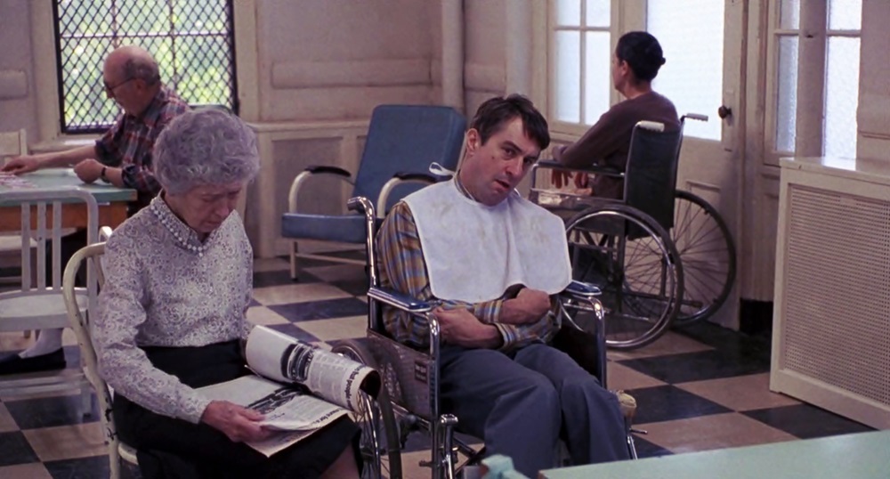 Robert De Niro es su papel de Leonard Lowe en silla de ruedas mientras su madre le lee una revista
