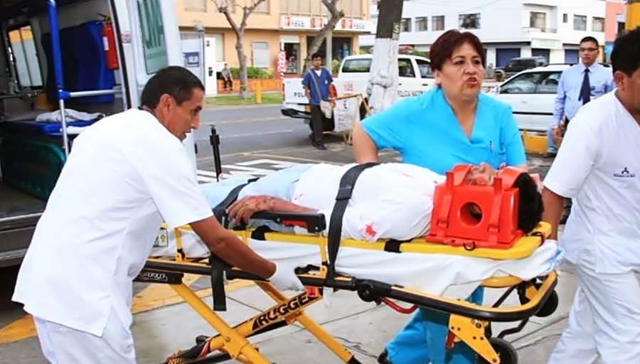Socorristas y médicos ingresan al hospital a un paciente inmovilizado del cuello en una camilla. 