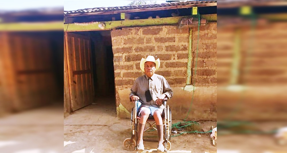 Fuera de su casa, de adobe, don Felino está sentado en si silla de ruedas. 