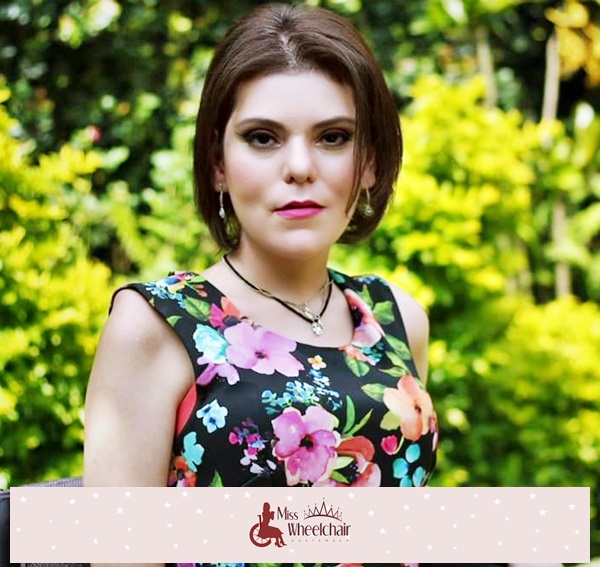 Fotografía de medio cuerpo, Rebeca Noemí Rodríguez Sánchez sonríe a cámara, viste un vestido negro estampado con flores 