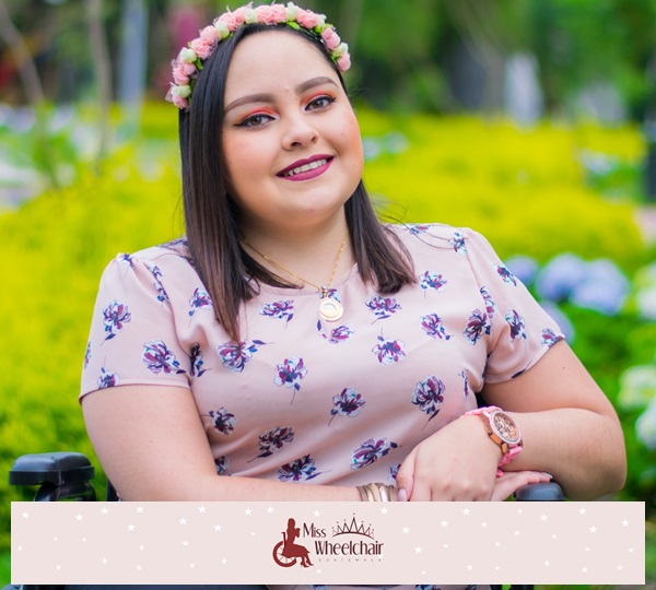 Fotografía de medio cuerpo, María Ximena Escobedo Mendoza sonríe a cámara vistiendo blusa rosada con estampados fucsia y una diadema en la cabeza hecha con florecitas rosadas  