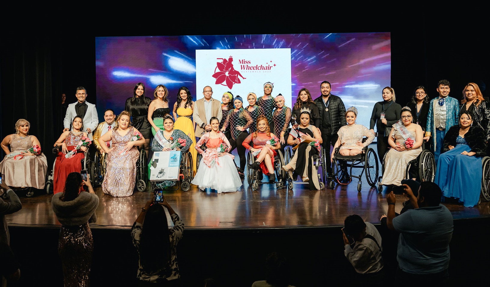 En un escenario posan para las fotografías artistas, jurado y candidatas Miss Wheelchair Guatemala 2023