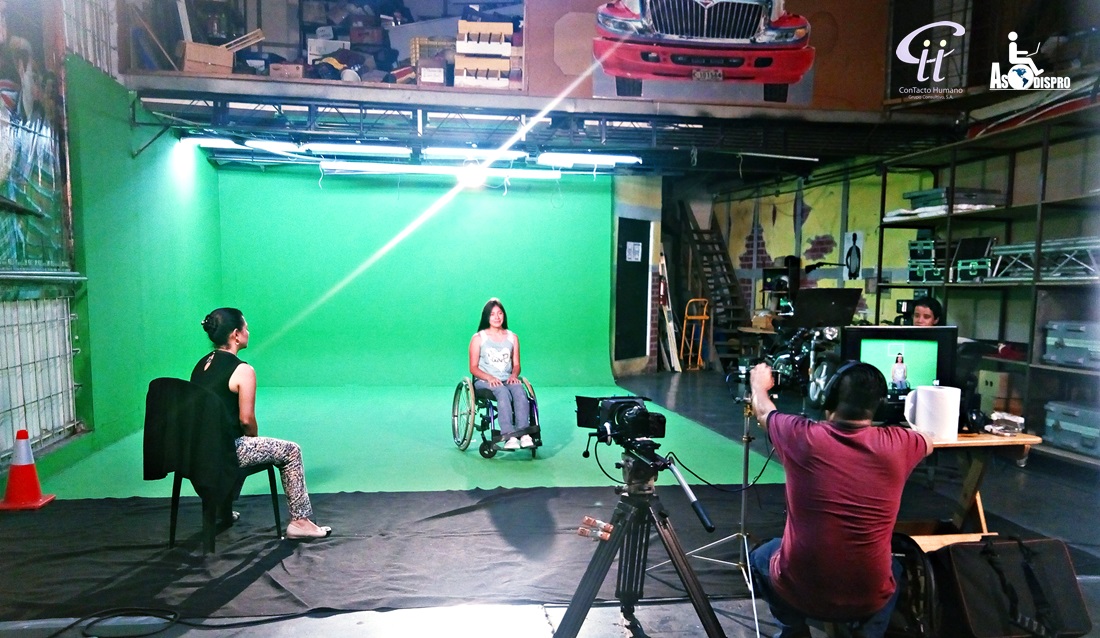 Durante una capacitación para videocurrículum, una chica en silla de ruedas está en un set de televisión mientras la Directora le hace preguntas y un técnico controla el equipo de grabación.