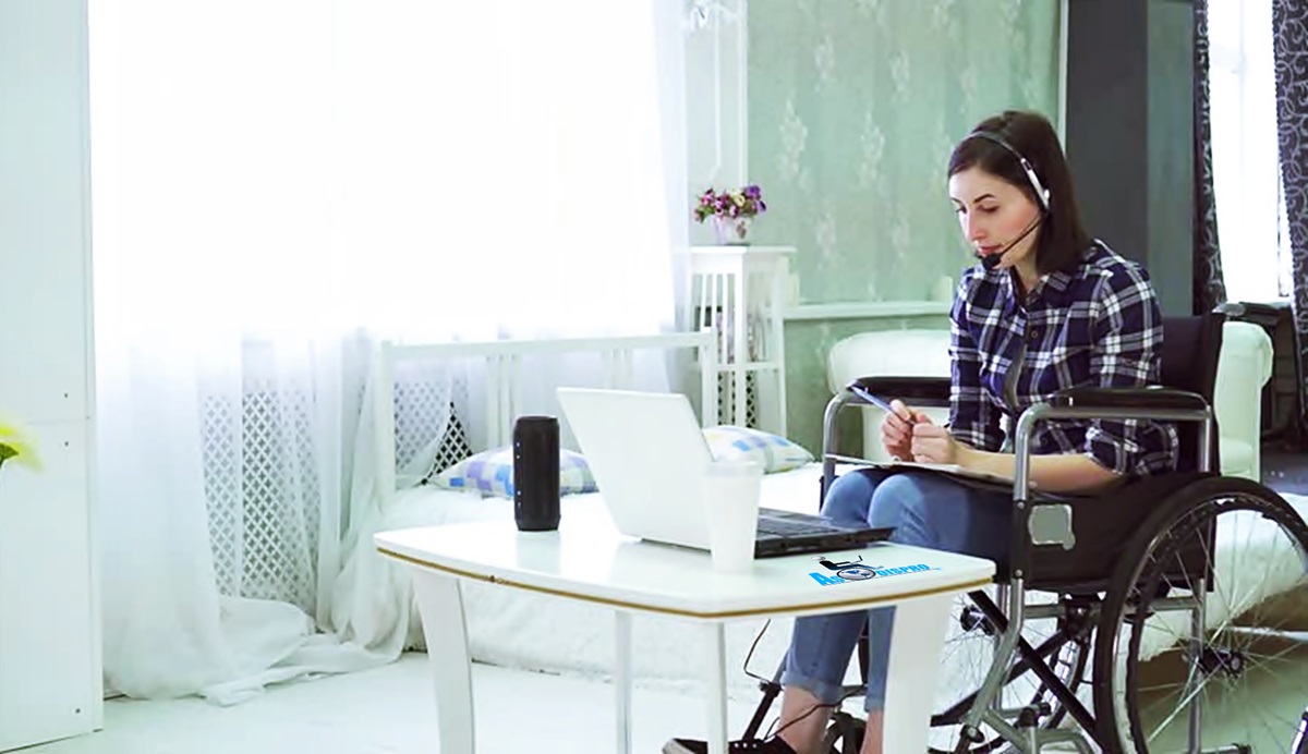 Una mujer en silla de ruedas trabaja en una computadora en una habitación