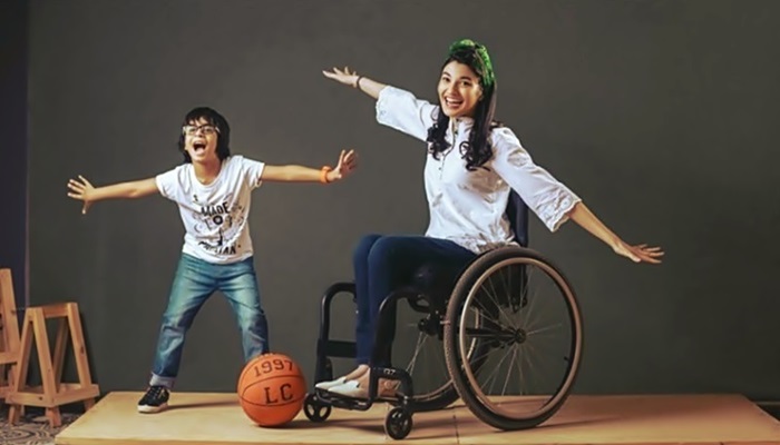 Un niño y una joven con discapacidad se divierten, mientras en el suelo hay una pelota de baquetbol 