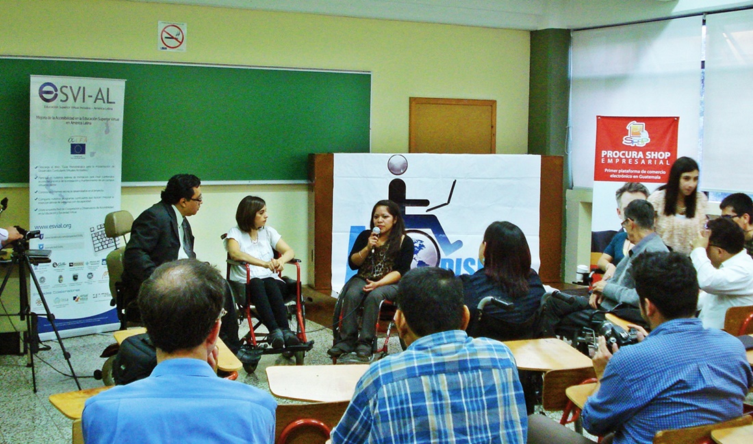 En un aula universitaria, 3 personas usuarias de silla de ruedas exponen ante una audiencia en Universidad Galileo