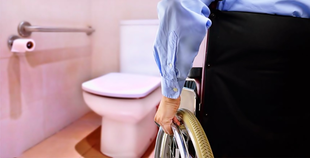 Un hombre en silla de ruedas se hacerca a un baño accesible 